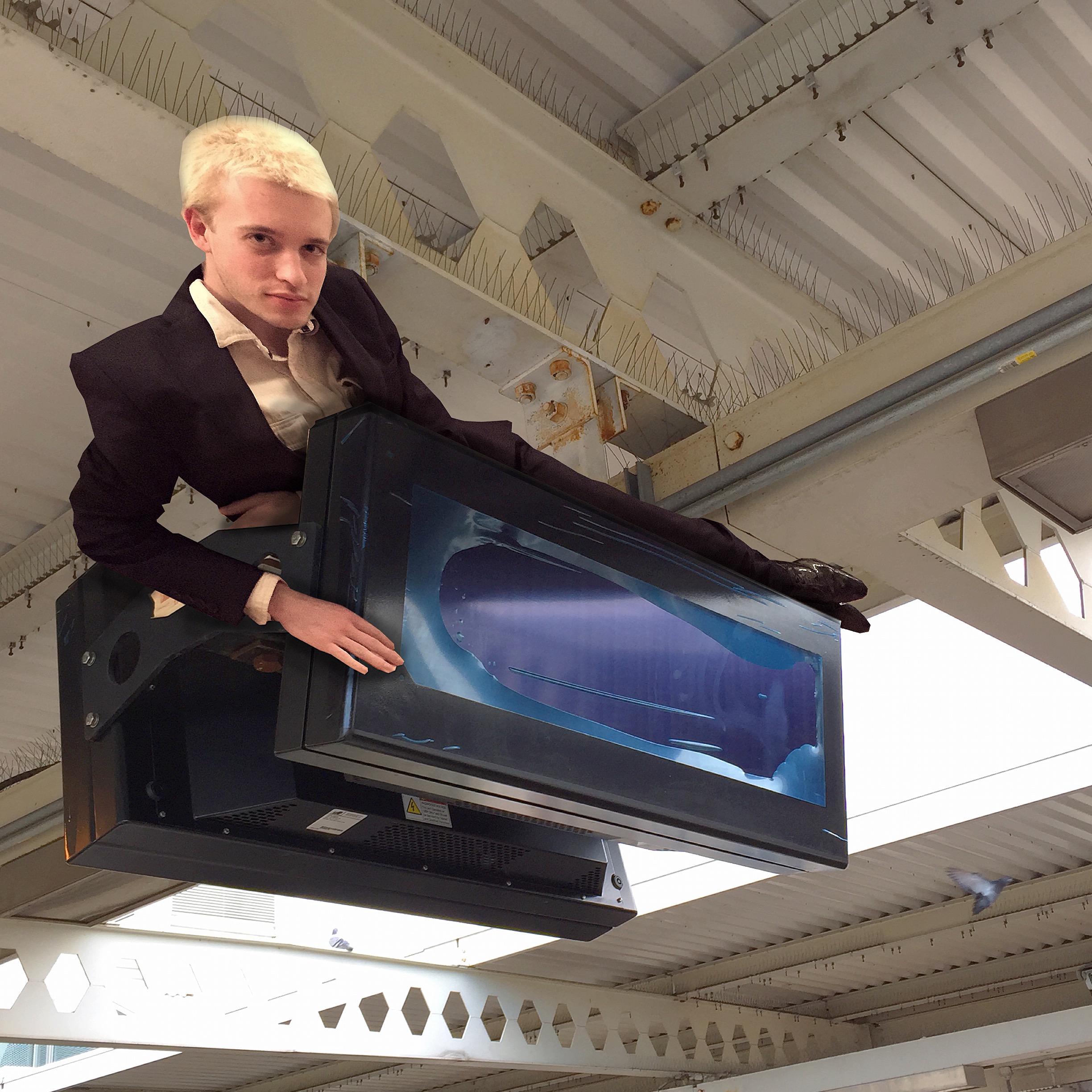 Butler laying across an LED information screen in a train station